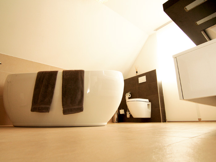 Minimalistisches Badezimmer mit moderner, runder Badewanne und wandhängender Toilette