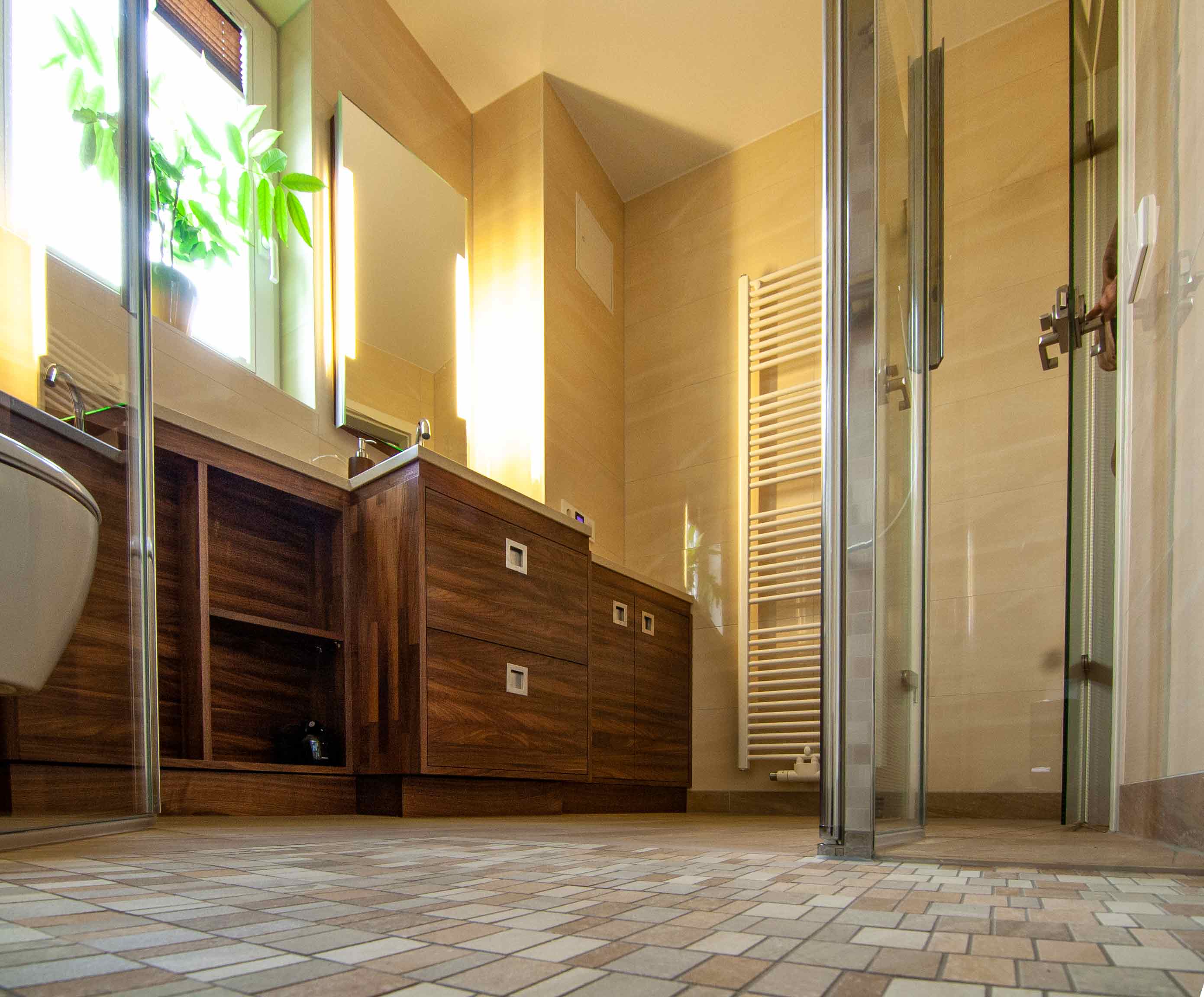 Bodengleiche Dusche mit kleinformatigen Fliesen in verschiedenen Größen in hellen und dunklen Brauntönen gefliest.