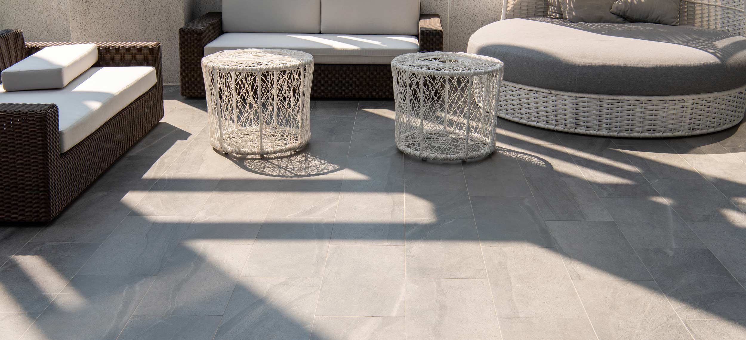 Terrasse mit grau marmorierten, großformatigen Fliesen und Sitzgarnitur