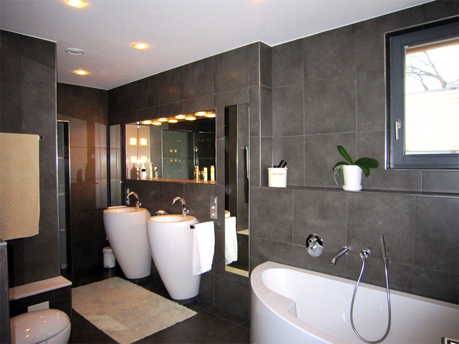 Badezimmer mit großformatigen, anthrazitfarbenen Fliesen und ABlageflächen durch Trockenbauweise. Spiegel & Licht in Trockenbauwand integriert.